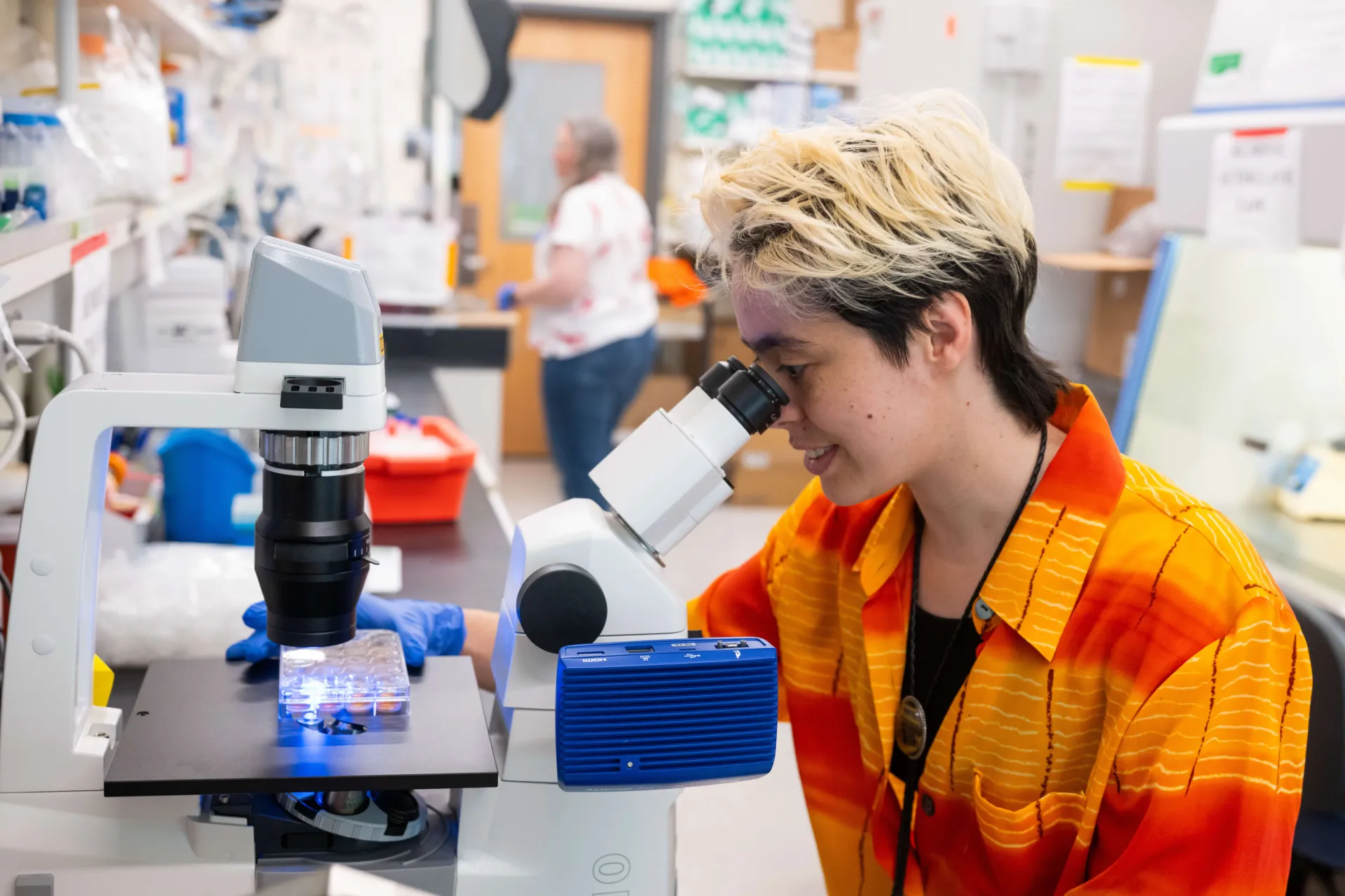 佛蒙特大学研究生在实验室使用显微镜开展登革热研究